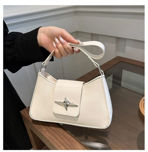 Detailed shot of cream leather baguette bag with silver star buckle and shoulder strap