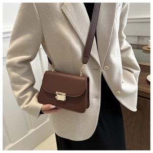 Detail of vintage brown crossbody bag with gold buckle and wide shoulder strap on model