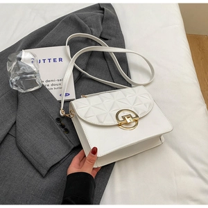 Detailed close-up of white crossbody bag with quilted diamond pattern and gold buckle