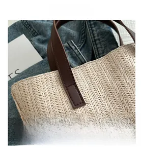 Close-up of woven straw tote bag with brown leather handle and fine herringbone texture
