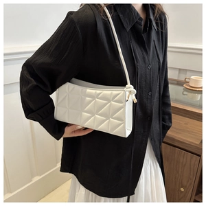 Detail of white geometric quilted crossbody bag with textured stitching and knot strap