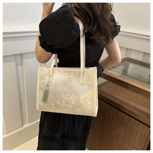 Détail de broderie florale et pompon en soie verte sur un sac cabas chinois