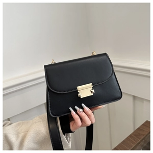 Detail of the golden rectangular metal buckle and matte leather texture on the small square bag
