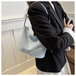 Detail of light blue shoulder bag with onwards and upwards embroidery on premium fabric