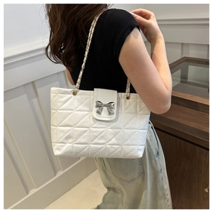 Detailed view of white quilted tote bag with silver bow clasp and chain strap