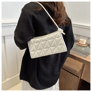 Detailed view of white leather shoulder bag with triangle quilted stitching and gold zipper