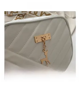Close-up of white V-quilted leather bag featuring golden deer charm and rectangular lock