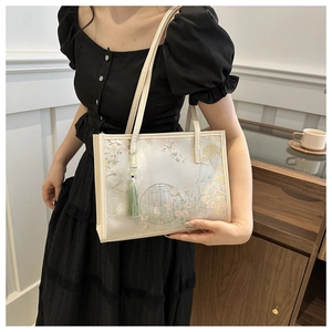 Detail of floral jacquard tote bag with elegant green tassel on a shoulder strap
