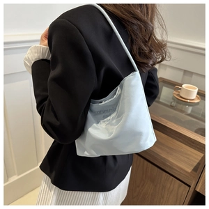 Detail of light blue shoulder bag with onwards and upwards embroidery on satin fabric