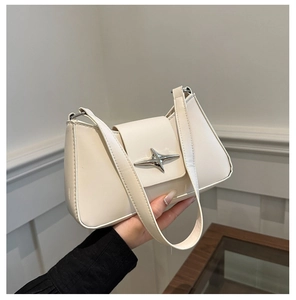 Close-up of cream-colored underarm bag with silver star buckle and faux leather texture