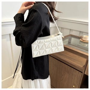 Detail of white quilted crossbody bag with geometric triangle patterns and thin strap