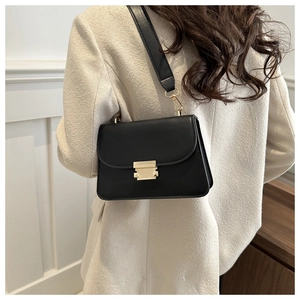 Close-up of black square crossbody bag with gold buckle on a model in tweed jacket