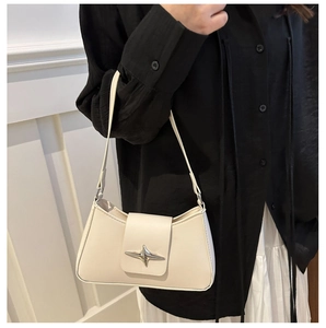 Chic beige underarm bag featuring a silver star ornament worn by a model in black shirt