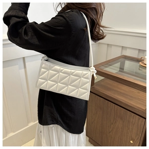 Detailed view of white crossbody bag with geometric triangle quilting and slim strap