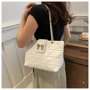 Detail of white quilted underarm bag with silver bow buckle and elegant metal chain strap
