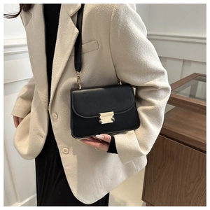 Classic black leather square bag with gold buckle worn on beige blazer suit