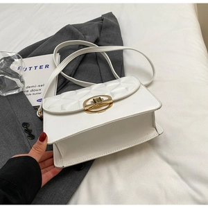 Detailed view of a white quilted crossbody bag featuring a golden oval metal buckle closure