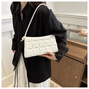 Chic white quilted shoulder bag with geometric stitching shown on a model in a modern room