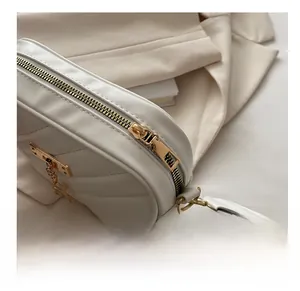 Close-up of smooth gold zipper and diagonal quilted leather on white crossbody bag
