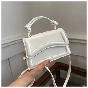 Detail of white handbag featuring a unique knotted handle and quilted flap design