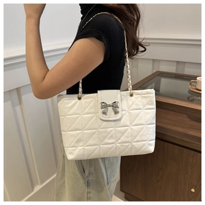 Detail of white quilted tote bag with silver bow clasp and metal chain strap