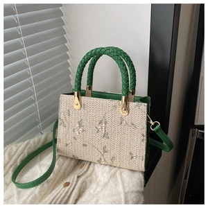 Detail of beige woven handbag with green floral embroidery and gold metal buckles