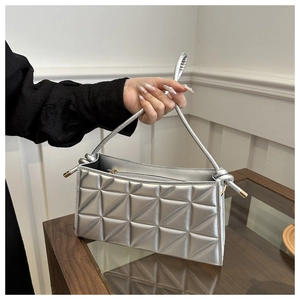 Detail of silver quilted handbag with geometric patterns and a twisted knot handle