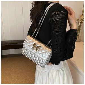Détail du sac bandoulière argenté matelassé avec boucle papillon sur modèle