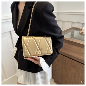 Golden quilted chain crossbody bag shown with a chic black blazer and white skirt outfit