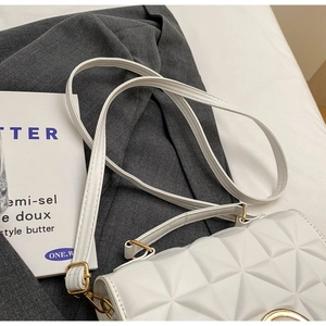 Close-up of white quilted crossbody bag with gold hardware and elegant metal handle