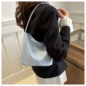 Detail view of a light blue satin shoulder bag with onwards and upwards embroidery