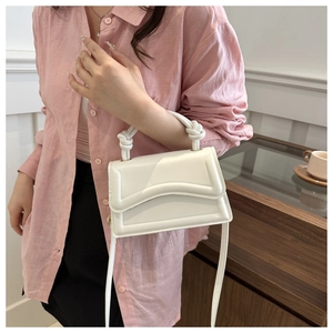 Detail of the white crossbody bag featuring a unique woven rope handle and sleek PU leather