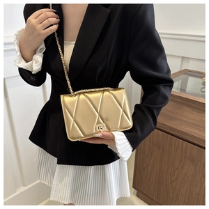Close-up of golden quilted chain crossbody bag with diamond stitching and metal clasp