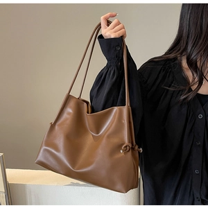 Detail shot of brown leather tote bag with side knot design for office commuters