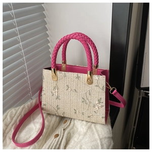 Detail of floral embroidery on cream straw bag with pink woven leather handle