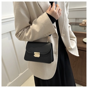 Detail of vintage black square bag with gold lock and stylish wide shoulder strap