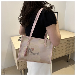 Gros plan du sac cabas rose brodé de fleurs avec pompon et fines bretelles élégantes