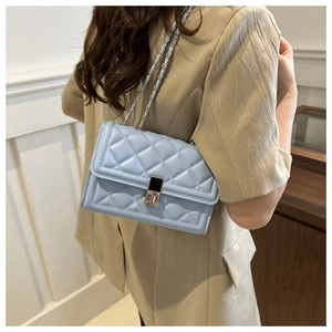 Detailed side view of light blue quilted crossbody bag with silver chain strap on model