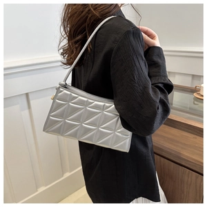 Silver metallic crossbody bag with geometric quilting shown worn by a model in lifestyle setting