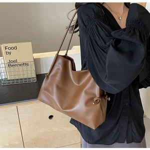 Detail of dark brown leather tote bag with stylish knotted shoulder strap on model