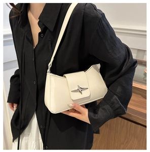 Detail of a white leather underarm bag featuring a silver star-shaped metal buckle on the flap