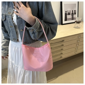 Detail of pink nylon shoulder bag with onwards and upwards embroidery on a model