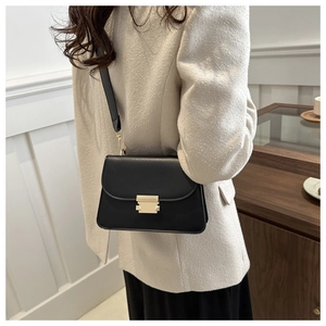Close-up of minimalist black crossbody bag featuring elegant gold rectangular metal clasp