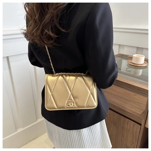 Detail of gold quilted leather crossbody bag with chain strap and metallic clasp closure