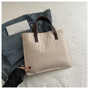 Close-up of beige woven tote bag with V-shaped texture and dark brown leather handles