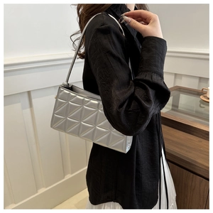 Detail of silver metallic quilted shoulder bag featuring geometric triangle stitching