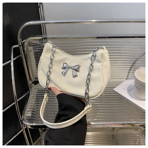 Detail of cream white shoulder bag with silver metallic bow and chain strap