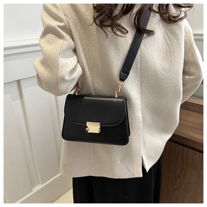 Rear view of model wearing black crossbody bag with gold lock and wide shoulder strap