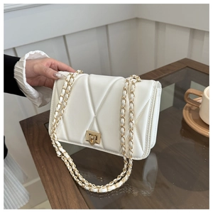 Detail of white quilted leather texture with gold metal chain strap and push-lock
