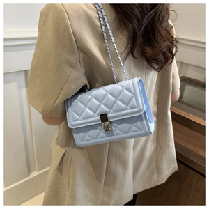 Detail of light blue quilted crossbody bag with silver chain and glossy finish
